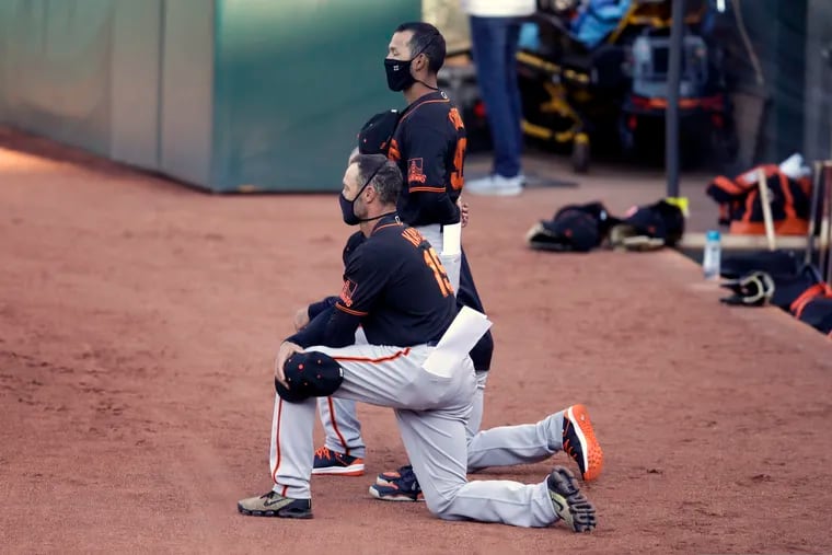 San Francisco Giants' manager Gabe Kapler kneels during the national anthem prior to an exhibition baseball game against the Oakland Athletics on Monday.