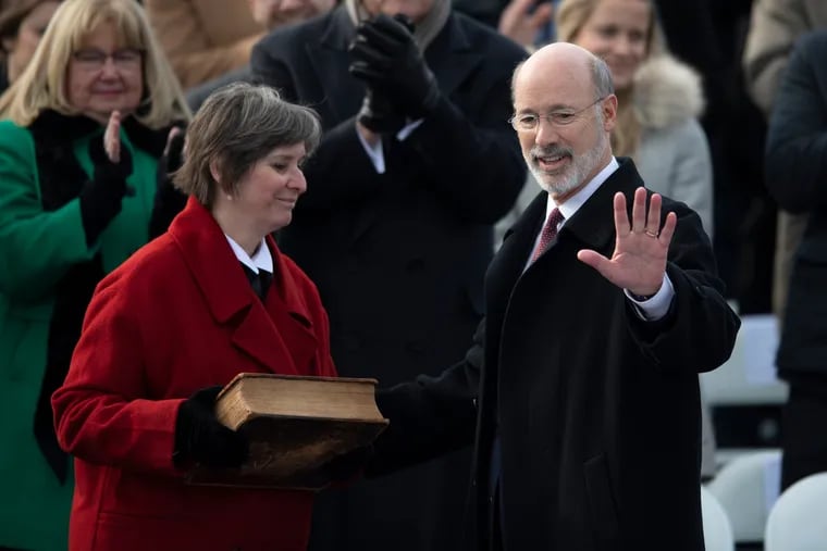 Pa. Gov. Tom Wolf, accompanied by his wife, Frances, waves to the crowed after taking the Oath of Office last week.