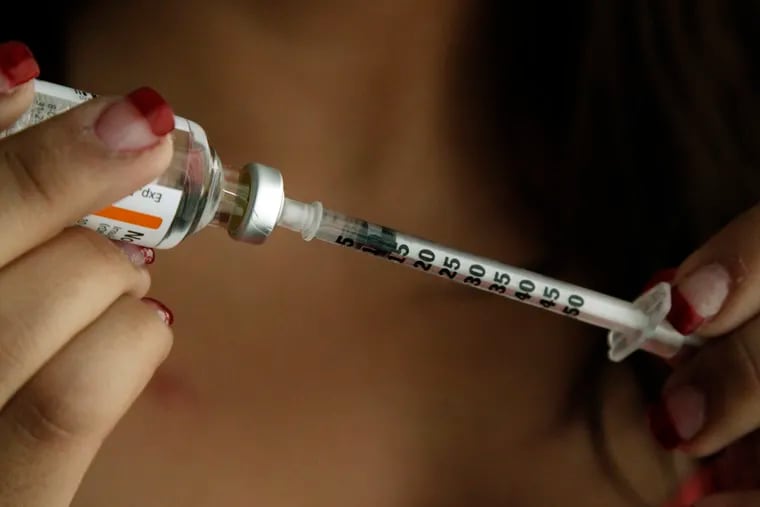 A teen fills a syringe as she prepares to give herself an injection of insulin at her home.