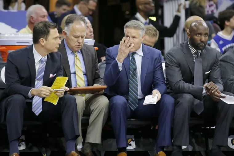 Sixers Head Coach Brett Brown (with hand up) sits on the bench with assistant coaches Billy Lange (left), Jim O’Brien (second left) and Lloyd Pierce (right) against the Toronto Raptors on Wednesday, January 18, 2017 in Philadelphia. Pierce interviewed for the Atlanta Hawks’ coaching job on Friday.