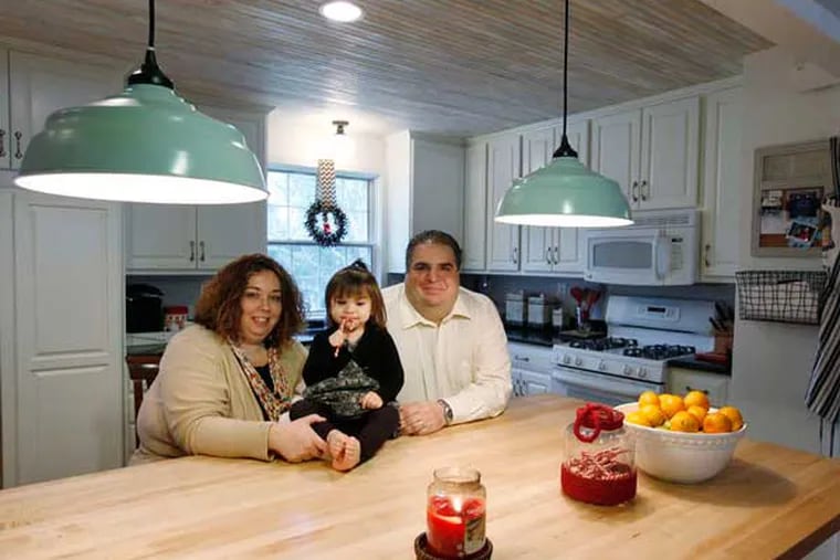 Jillian and Chris Soriano and daughter Tessa, 2, in the newly renovated kitchen of their home in Haddon Heights. They opened up a wall, added the center island, and upgraded cabinets and appliances. ( MICHAEL S. WIRTZ / Staff Photographer).