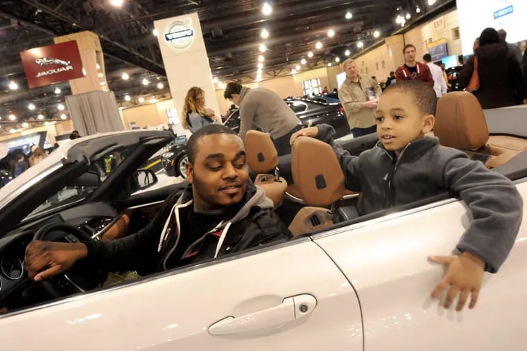 Sam Ellison and his son Sam Jr., 5, try out a ride at the 2014 Auto Show.