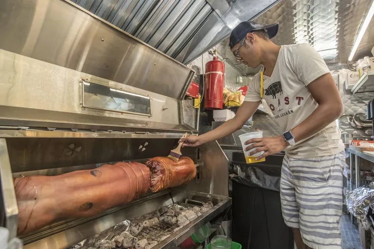Chef John Peralta brushes oil on the two pigs he has on the custom-made whole-hog spit in his food truck, Roast