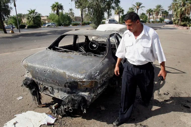 FILE - In this Sept. 25, 2007 file photo, an Iraqi traffic policeman inspects a car destroyed by a Blackwater security detail in al-Nisour Square in Baghdad, Iraq. A federal jury convicted four former Blackwater security guards in 2014 for the killing and wounding of 31 Iraqis civilians in the heart of Baghdad. President Donald Trump on Tuesday, December 22, 2020, pardoned 15 people, including the four Blackwater contractors.