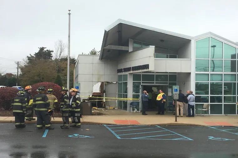 Firefighters stand near where a car drove into a Social Security office i Egg Harbor Township, N.J.