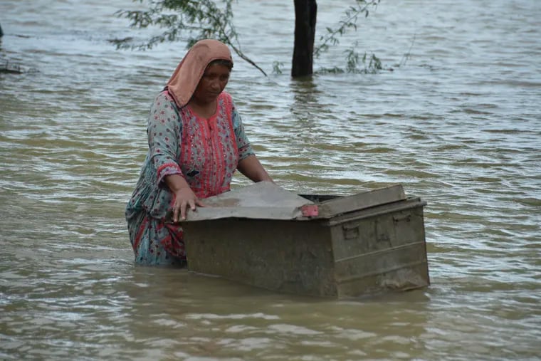 A woman uses a trunk to salvage usable items from her flood-hit home in Jaffarabad, a district of Pakistan's southwestern Baluchistan province, on Aug. 25.