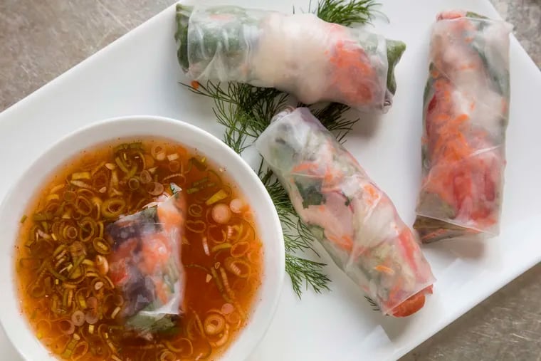 Filled with brilliantly hued garden vegetables, colorful summer rolls are served with dipping sauce.