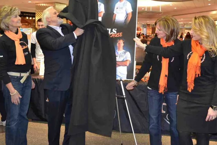 Bernie Parent unmasks the program cover for the Flyers Wives Fight for Lives Carnival in the Comcast Center's food court. With the Hall of Fame goaltender Wednesday were (from left) Doreen Holmgren, wife of general manager Paul Holmgren; Elaine Reese, wife of goalie coach Jeff Reese; and Lisa Hanrahan, wife of assistant general manager Barry Hanrahan. The carnival will be held Feb. 27 at the Wells Fargo Center.
