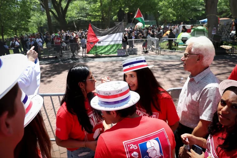 University of Pennsylvania students participating in Hey Day stand across from a pro-Palestinian encampment on the College Green in Philadelphia on Thursday.