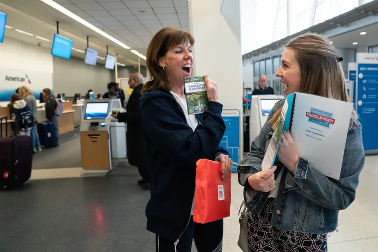 Kate (left) and Tess Donlevie open a mystery envelope from a travel agent that specializes in mystery trips. The mother and daughter opened their surprise travel itinerary at the Philadelphia International Airport.