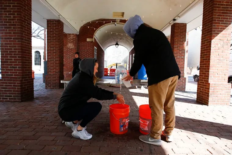 Shoppers Alex Fluharty (left) and Mike Furey wash their hands at a makeshift area at the Headhouse Farmers' Market in the Society Hill section of Philadelphia.