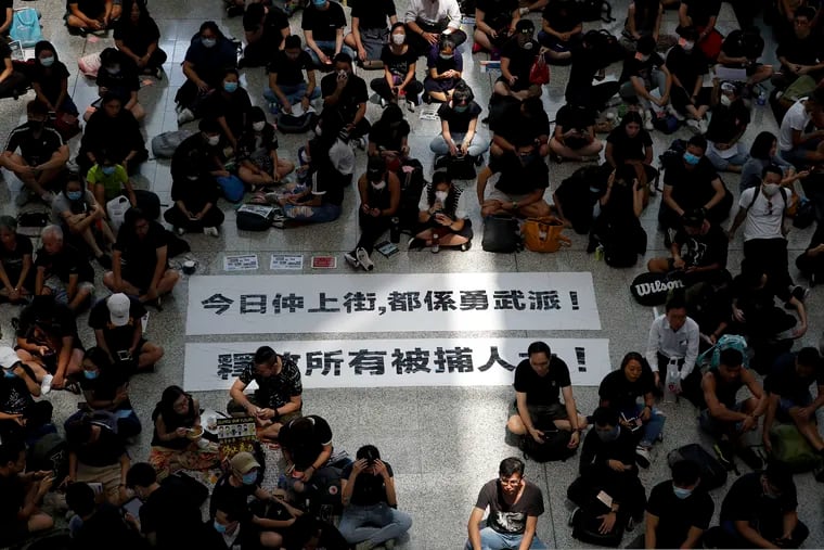 Protesters surround banners that read: "Those on the street today are all warriors!" top, and "Release all the detainees!" during a sit-in rally at the arrival hall of the Hong Kong International airport, Monday, Aug. 12, 2019. Hong Kong police showed off water cannons Monday as pro-democracy street protests stretched into their 10th week with no sign of either side backing down.