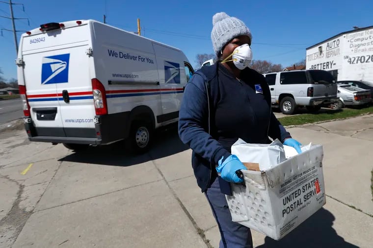 A United States Postal worker makes a delivery with gloves and a mask in Warren, Mich., Thursday, April 2, 2020.