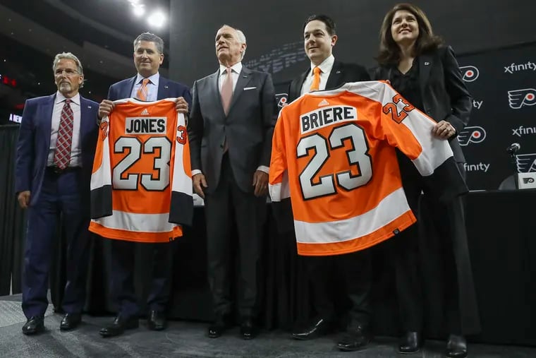 From left, John Tortorella, Keith Jones, Dan Hilferty, Daniel Brière, and Valerie Camillo pose with jerseys for Jones and Brière during the Flyers' press conference at the Wells Fargo Center on Friday.