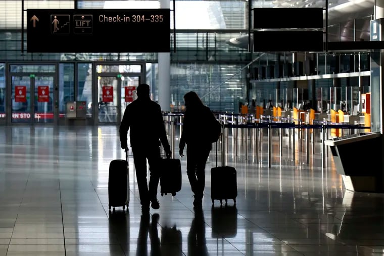 People walk with their luggage through a deserted check-in hall at the airport in Munich, Germany as Germany in December.