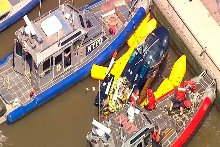 In this image made from video provided by WABC-TV, harbor units from the New York City police and fire departments work to secure a helicopter to the dock after it crashed in the Hudson River, Wednesday, May 15, 2019 in New York. WABC reports that the pilot was ok and that there were no passengers on the aircraft.