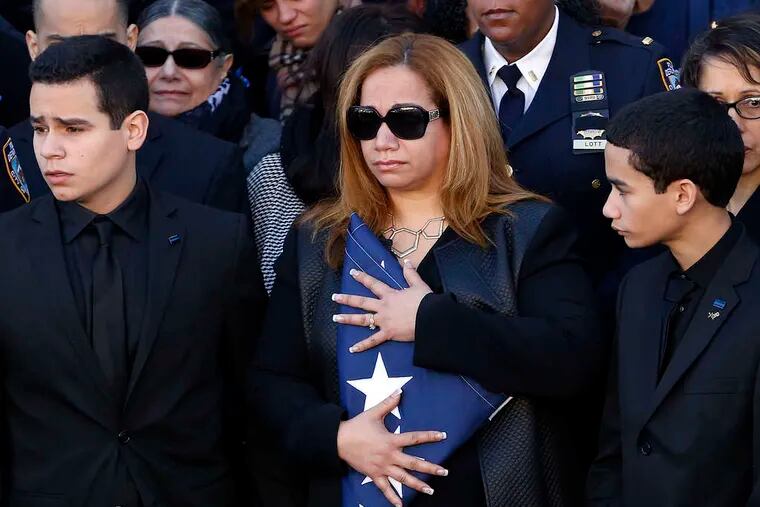 Maritza Ramos holds a flag while flanked by sons Justin (left) and Jaden at the funeral for her husband, Police Officer Rafael Ramos, at Christ Tabernacle Church in Queens.