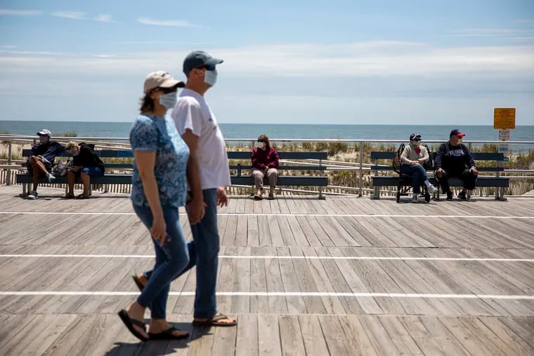Two people wearing mask walk along the boardwalk in Ocean City while enjoying the weather and the view of the beach on Saturday May, 16, 2020. Ocean City is one of few beaches doing a “dry run” to test “capacity management” this weekend in preparation for Memorial Day.