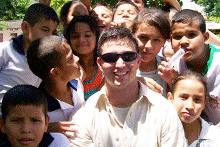Joe Malizia is surrounded by children during stint in Colombia.