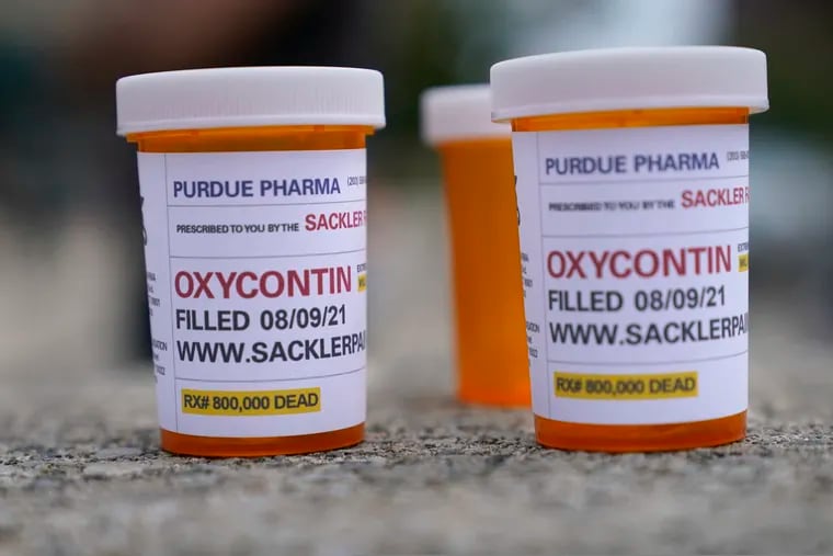FILE - In this Aug. 9, 2021, file photo, fake pill bottles with messages about OxyContin maker Purdue Pharma are displayed during a protest outside the courthouse where the bankruptcy of the company is taking place in White Plains, N.Y. A federal bankruptcy judge on Wednesday, Sept. 1, gave conditional approval to a sweeping, potentially $10 billion plan submitted by OxyContin maker Purdue Pharma to settle a mountain of lawsuits over its role in the opioid crisis that has killed a half-million Americans over the past two decades. (AP Photo/Seth Wenig, File)
