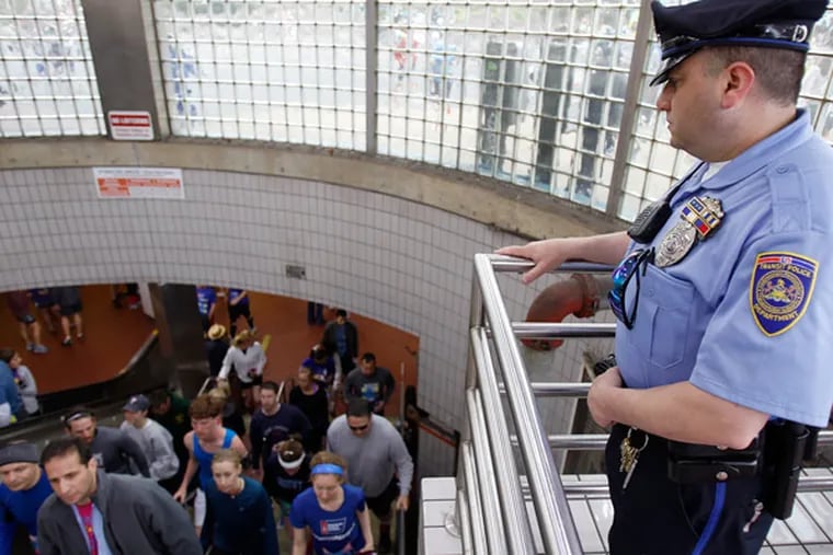Transit Officer Douglas Ioven watches as people exit the Olney subway stop before the start of the race. (David Maialetti / Staff Photographer)