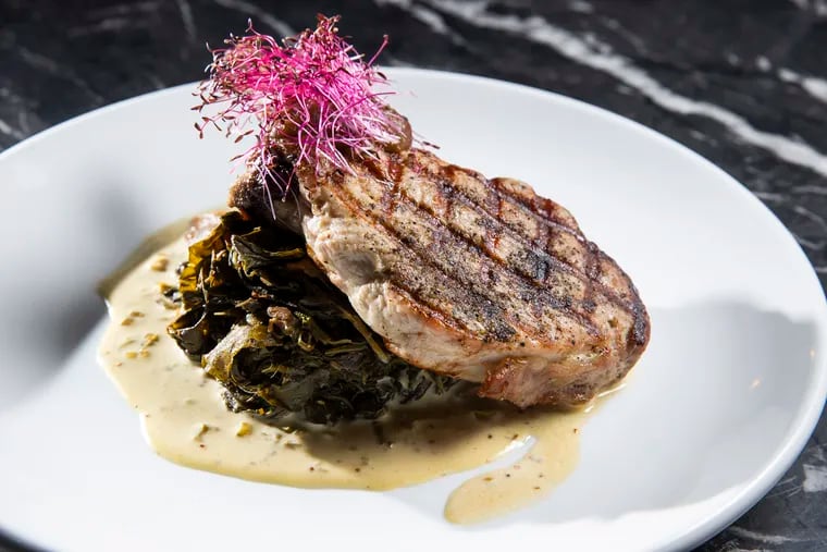 Fourteen-ounce duroc bone-in pork chop, sweet-and-sour braised collards, apple butter, and grain mustard sauce at Rex at the Royal on Dec. 29, 2021.