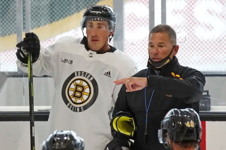 Bruins winger Brad Marchand, shown with head coach Bruce Cassidy during the team's camp on July 13, is cleared from injury and will play Sunday against the Flyers.