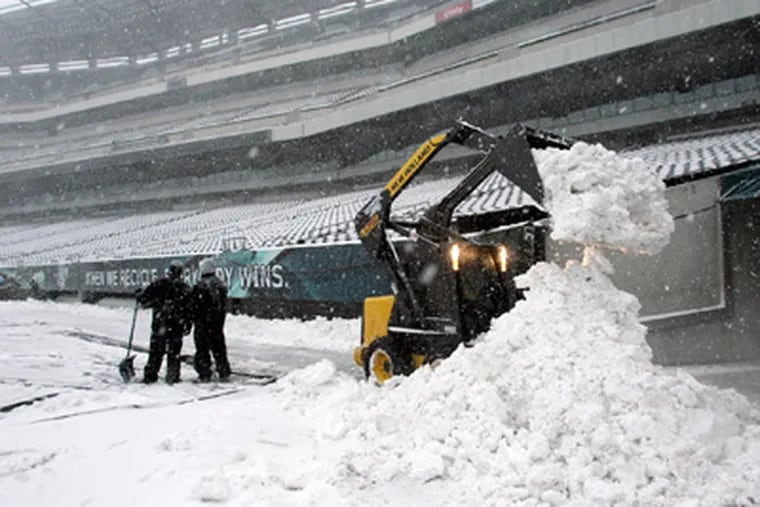Workers move snow inside Lincoln Financial Field as it falls on the field on Sunday. (Yong Kim / Staff Photographer)
