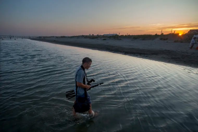 A photographer wades through a flooded area of the Avalon beach in August; minor to moderate flooding is possible during the weekend.