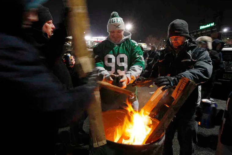 It was a barrel of laughs keeping warm for some fans, and hot food was a necessity. At right, Dave Gauntt cooks for his brother, Kevin, of Mount Laurel.
