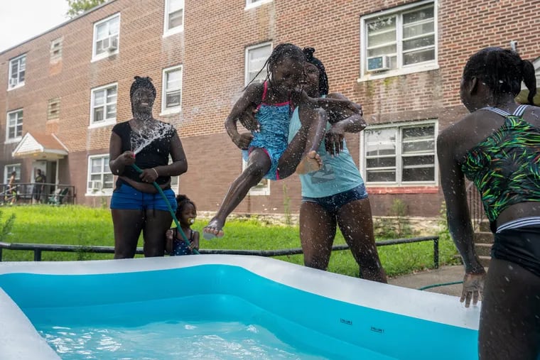 Nyala Johnson, 6, is thrown into a blow up pool by her mother, Helen Johnson, outside their home in Southwest Philadelphia on Friday.