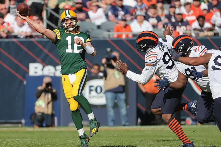Green Bay Packers quarterback Aaron Rodgers passes under pressure from the Chicago Bears' Robert Quinn (94) and Eddie Goldman (91) at Soldier Field on Oct. 17, 2021, in Chicago. (Jonathan Daniel/Getty Images/TNS)