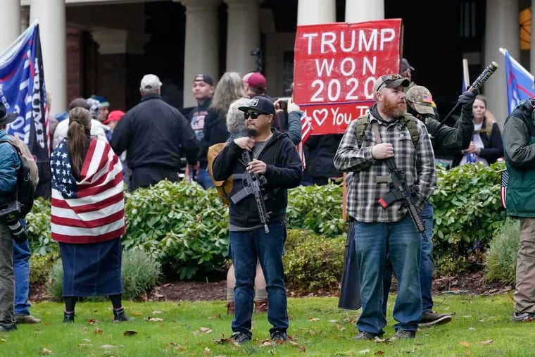 Two men standing armed with guns on Jan. 6, 2021, in front of the governor's mansion in Olympia, Wash., during a protest supporting then-President Donald Trump and against the counting of electoral votes in Washington, D.C., affirming then-President-elect Joe Biden's win.