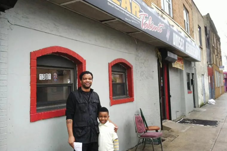 Takyi Williams, pictured outside his South Philadelphia barbershop with son Takyi Jr., says the Philly311 app has made it easier for him to focus on his business. (Morgan Zalot / Daily News Staff)