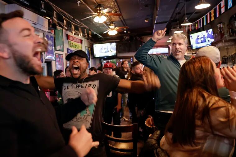Brandon Baugham of Jersey City (middle, wearing ball cap), Sean Iaquinto of Hoboken (standing at right), and other members of the Philadelphia Eagles Club of Hoboken sing “Fly Eagles Fly” after watching the Birds beat the Saints on Sunday.