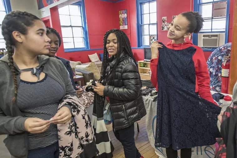 India Cannon,  right, holds up a dark blue dress for Taicha Ramos, 14, left, to offer her opinion as these girls sort through new dresses donated to them at the Wissahickon Boys &amp; Girls Club by the Believe in Yourself Project.