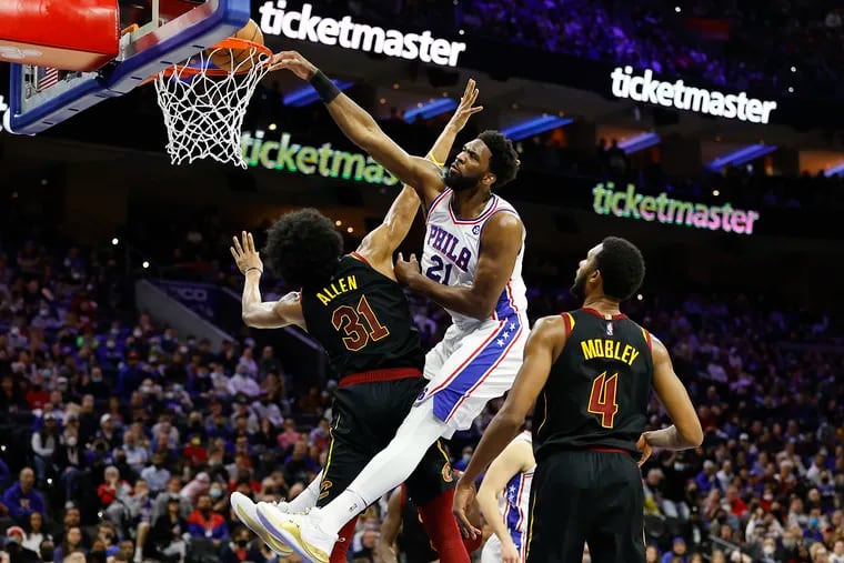 Sixers center Joel Embiid dunks the basketball over Cleveland Cavaliers center Jarrett Allen and forward Evan Mobley in the second quarter on Saturday, February 12, 2022 in Philadelphia.