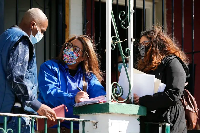 Esperanza vice president of community organizing Quetcy Lozada (center) and Esperanza community outreach coordinator Jasmin Velez (right), help register resident Jeff Harris for a COVID-19 vaccination in the Hunting Park neighborhood on Monday.
