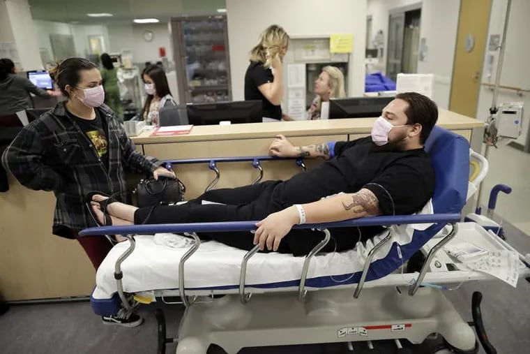 Donnie Cardenas, on bed, waits with his roommate Torrey Jewett at Palomar Medical Center in Escondido, Calif., Jan. 10, 2018. Cardenas had the flu.