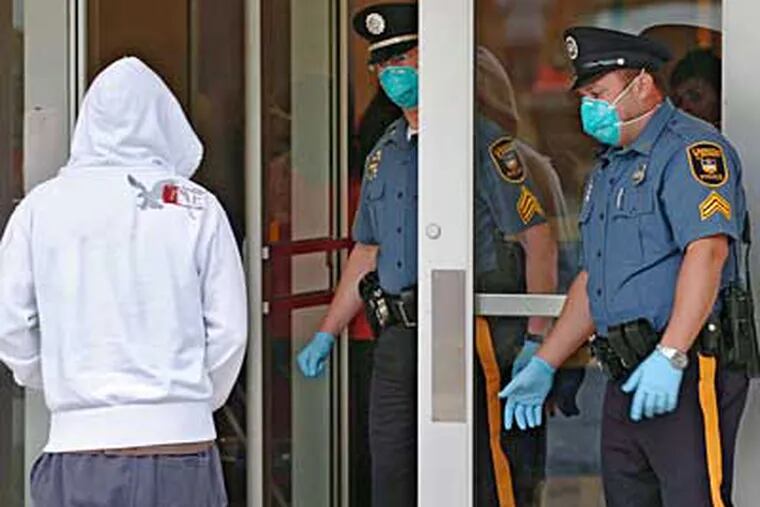 University of Delaware police watch as a student enters the Carpenter Sports Building where a temporary health clinic is set up to evaluate students who think they may have swine flu, (Clem Murray/Philadelphia Inquirer/MCT)