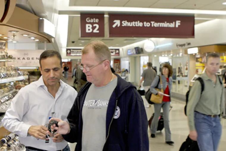 Ben Cohen (left), owner of the Time to Fly kiosk at Philadelphia International Airport, shows Shawn McElroy a watch. (Michael S. Wirtz / Staff Photographer)