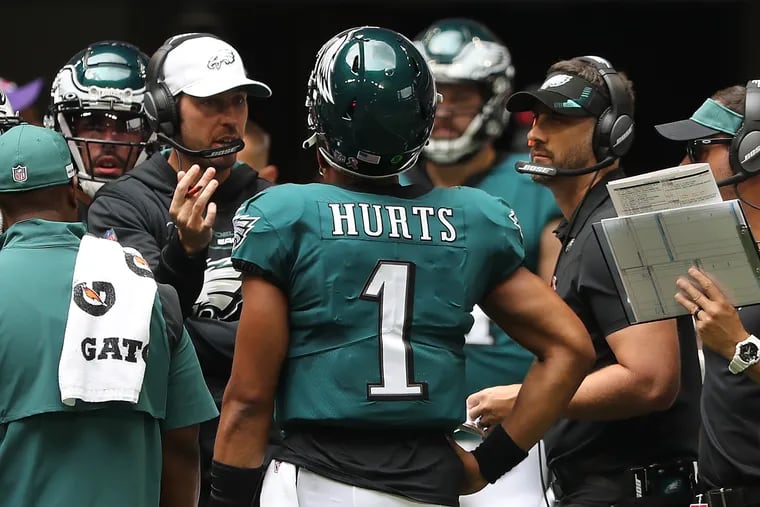 Eagles offensive coordinator Shane Steichen (left) and coach Nick Sirianni (right) talk to quarterback Jalen Hurts during a game against the Falcons on Sept. 12.