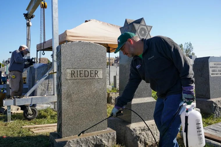 Joe Ferrannini (left) smooths the base of a gravestone, while Adam Denish cleans another at the Har Nebo Cemetery in  Northeast Philadelphia. Ferrannini is a professional gravestone conservator and Denish is a volunteer; they are part of a pilot project coordinated by the Jewish Federation of Greater Philadelphia.