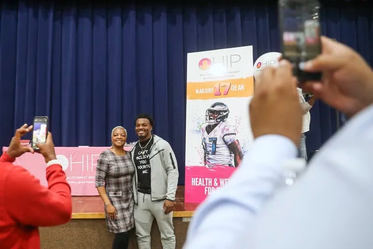 Nakobe Dean, rookie linebacker with the Philadelphia Eagles, takes a picture with his mother, Neketta Dean, after speaking in the auditorium at C.C.A. Baldi Middle School in Philadelphia on Tuesday, Oct. 25, 2022. Dean is touring schools to address oral and vision treatments, as well as education and health gaps for youths. Dean’s parents instilled in him the value of education, health, and community service from a young age.