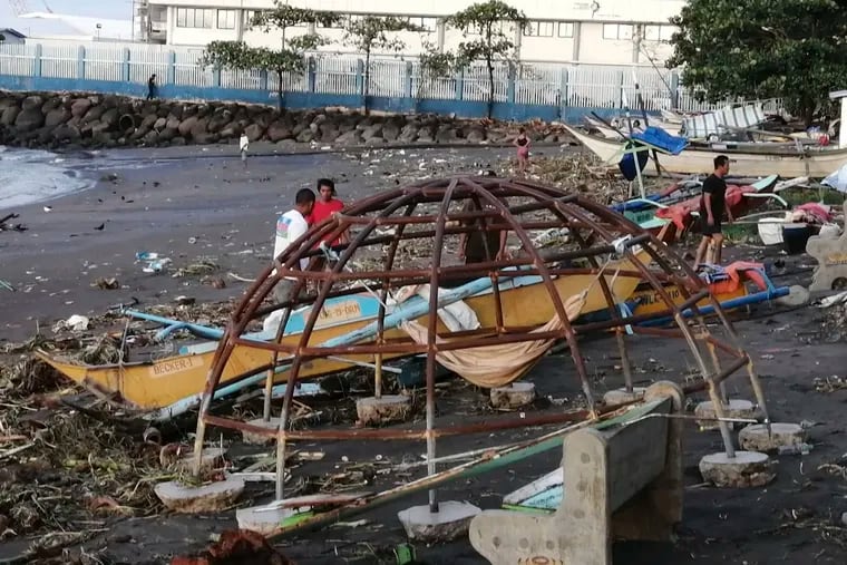 Residents walk beside an outrigger and playground equipment that were damaged by Typhoon Phanfone along a coastline in Ormoc city, central Philippines on Thursday. The typhoon left over a dozen dead and many homeless.