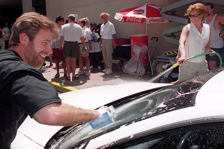 WIP's Howard Eskin and 6ABC meteorologist Cecily Tynan cleaning a cab during a celebrity car wash at the Wyndham Franklin Plaza Hotel in 1999.
