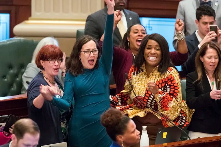 Illinois state Rep. Kelly Cassidy, D-Chicago, throws her fist in the air as she celebrates with Illinois state Senator Heather Steans, D-Chicago, left, and Rep. Jehan Gordon-Booth, D-Peoria, as they watch the final votes come in for their bill to legalize recreational marijuana use in the Illinois House chambers Friday, May 31, 2019. The 66-47 vote sends the bill to Gov. J.B. Pritzker who indicated he will sign it. (Ted Schurter/The State Journal-Register via AP)