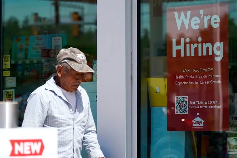 A hiring sign is displayed at a gas station as a customer walks past in Buffalo Grove, Ill.