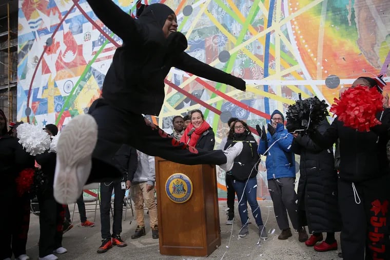 Cheerleader Najah Thomas, a senior, leaps as confetti falls to mark the dedication for a new mural at South Philadelphia High School.