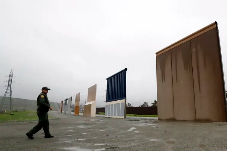 FILE - In this Feb. 5, 2019 file photo a Border Patrol agent walks towards prototypes for a border wall in San Diego. The Trump administration on Wednesday, Feb. 27 plans to demolish eight prototypes of the president's prized border wall that the government built near San Diego one year ago.